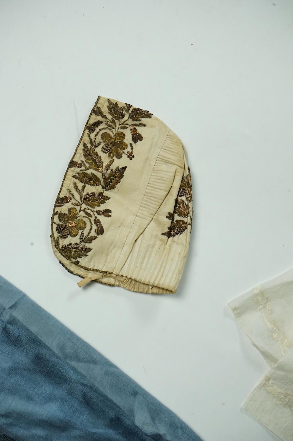 An early 19th century cream silk and metal thread embroidered ladies bonnet, an interesting 1930’s blue silk and gold thread dress fabric designed with Secessionist influences, an earlier fine linen silk embroidered kerc